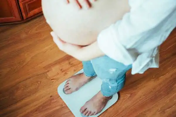 Image of woman weighing herself and experiencing weight gain through pregnancy Shoreham Beach